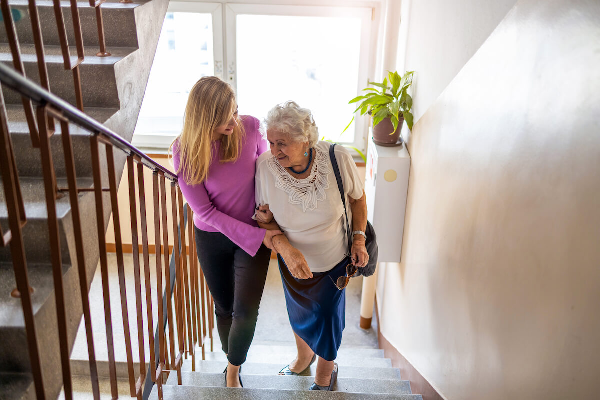 woman helping older woman up the stairs_home safety tips for seniors