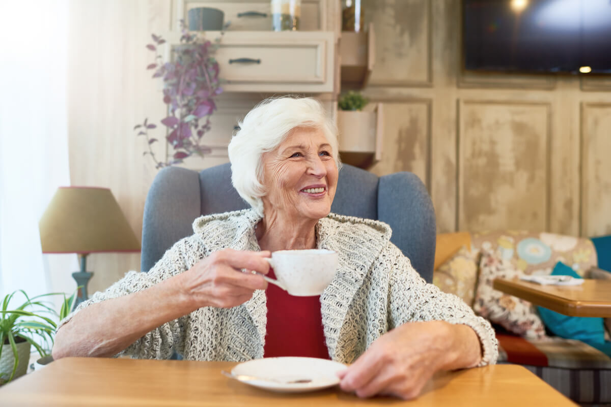happy senior woman drinking tea in assisted living 