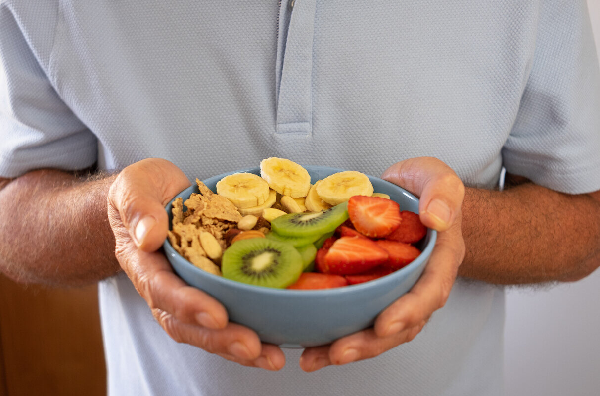 Senior man ready to eat a salad of fresh and dried fruits. Breakfast or lunch time, healthy eating