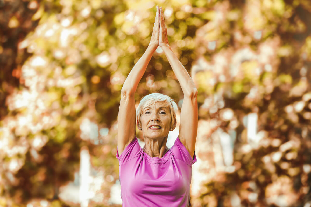 Senior woman doing yoga exercises at park.
